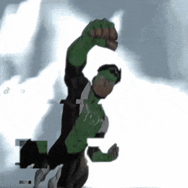 a man in a green and black superhero costume is holding his fist up in the air .