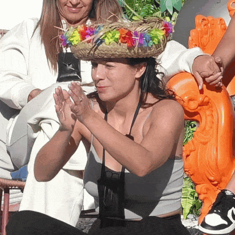 a woman wearing a hat with flowers on it is clapping