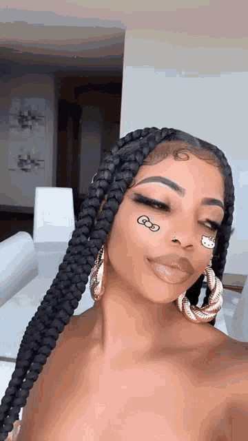 a woman with braids and a hello kitty tattoo on her face