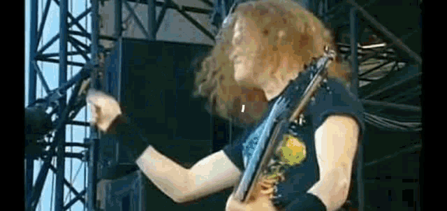 a man is playing a guitar on a stage in front of a crowd .