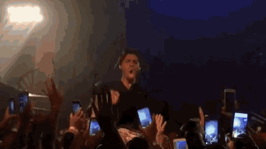 a man singing into a microphone in front of a crowd of people