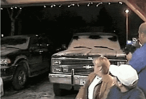 a group of people are standing in front of a gmc truck in a garage