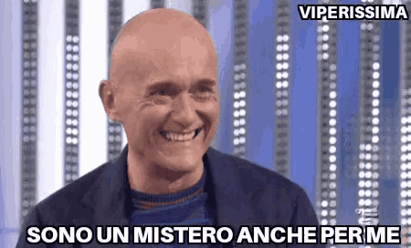 a bald man is smiling with the words sono un mistero anche per me written below him
