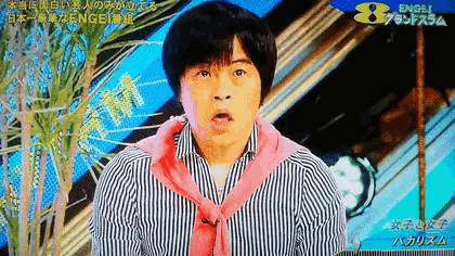 a man in a striped shirt with a pink scarf around his neck appears on a television screen