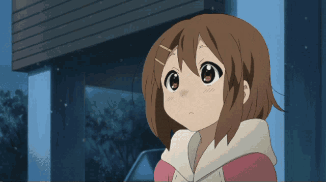a girl with brown hair and a pink sweater looks at the camera with a serious look on her face
