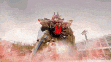 a robot with a sword and shield is standing in a field of red smoke .