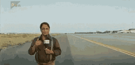 a man is standing on the side of a road with a microphone .