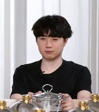 a man in a black shirt is holding a pot with a lid .