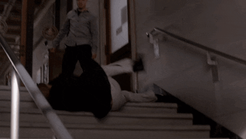 a man is falling down a set of stairs with a handrail