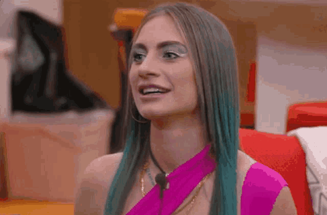 a woman with blue hair is wearing a pink top