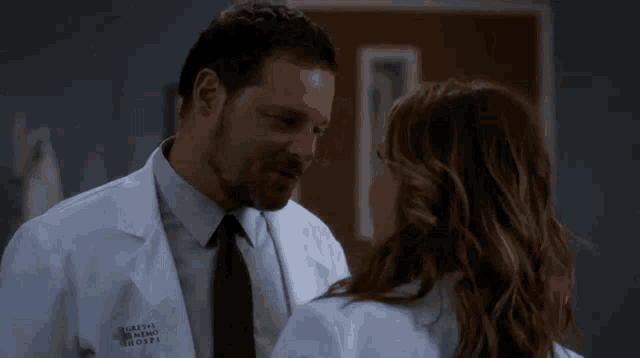 a man and a woman are looking at each other and the man is wearing a grey 's anatomy hospital coat