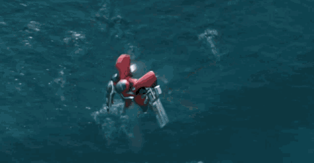 a red robot is flying over a body of water with a shark in the background