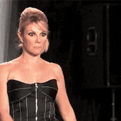 a woman in a black strapless dress is standing on a runway .