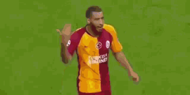 a soccer player in a yellow and red jersey is standing on a field .