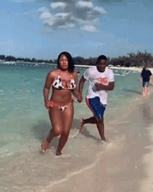 a woman in a bikini and a man in shorts are walking on the beach