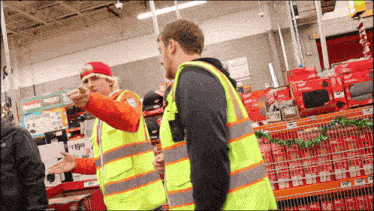 two men in safety vests are standing in front of a sign that says ridgid