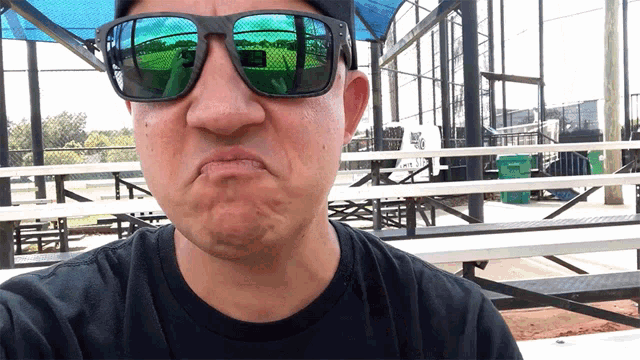 a man wearing sunglasses and a black shirt making a face