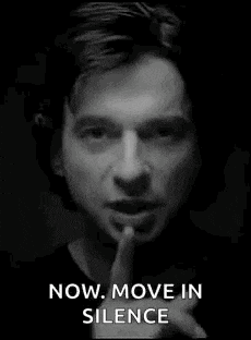 a black and white photo of a man holding his finger to his mouth .