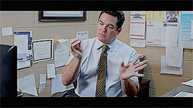 a man in a white shirt and tie is sitting at a desk in front of a computer