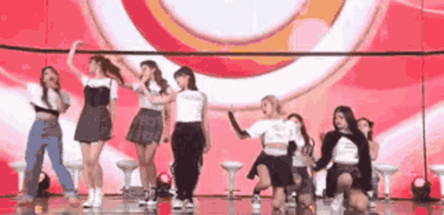 a group of girls are dancing on a stage in front of a red background .