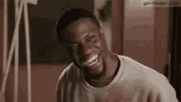 a man with a beard is laughing while wearing a white shirt .