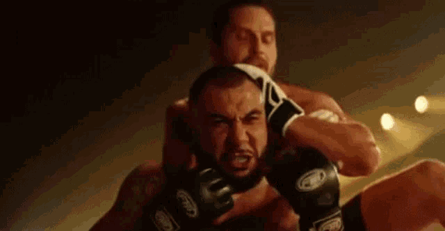 two men are fighting in a boxing ring and one is holding the other 's neck .