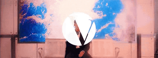 a woman is standing in front of a painting with a circle in the middle of it .