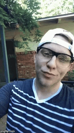 a man wearing glasses a hat and a striped shirt takes a selfie