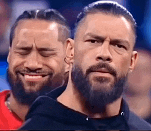 a man with a beard is standing next to another man with a beard making a funny face .