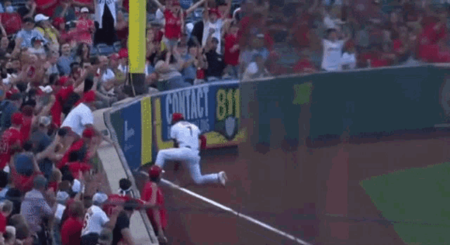 a baseball player is getting ready to catch a ball while a crowd watches .