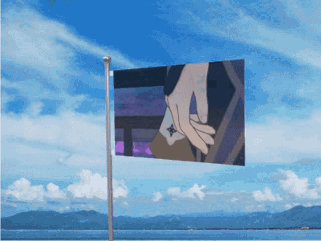 a flag with a picture of a person 's hand on it is flying in front of the ocean