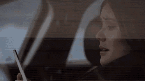 a woman is sitting in a car looking at her cell phone
