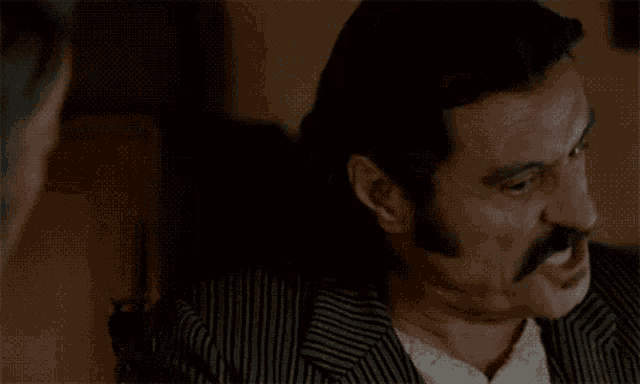 a man with a mustache is wearing a striped suit and a white shirt
