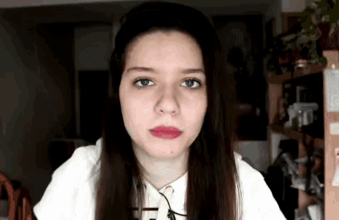 a woman wearing glasses looks at the camera with a serious look on her face