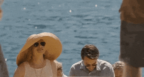 a woman wearing a straw hat is standing next to a man and a woman .