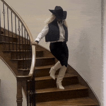 a woman wearing a black hat and white boots is walking down a set of stairs