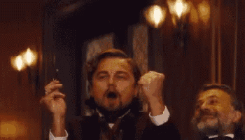 two men in suits are raising their fists in the air .