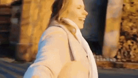 a woman is walking down the street with her arms outstretched and smiling .