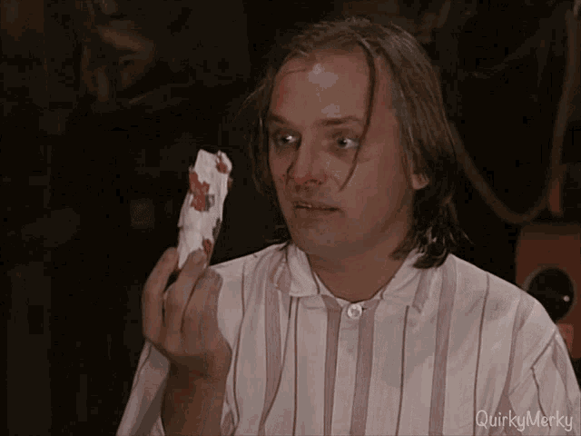 a man with a bloody nose is holding a piece of paper that says quirky merky on the bottom