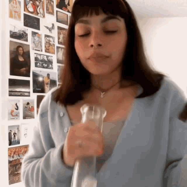 a girl in a blue sweater is smoking a bong