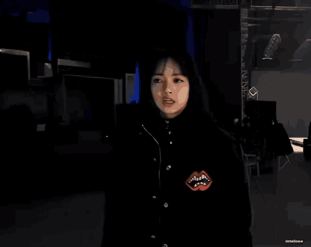 a woman wearing a black jacket with a red mouth on it giving the peace sign