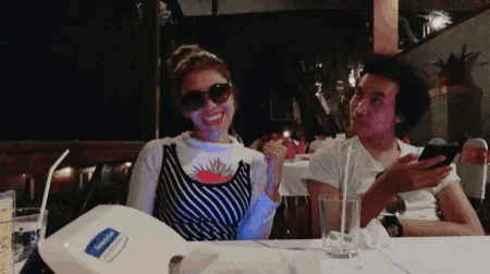 a man and a woman sit at a table with a napkin holder that says vaseline on it