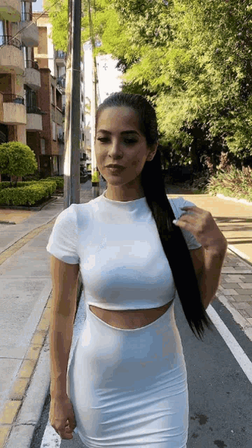 a woman in a white dress walking down the street