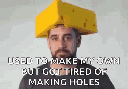 a man with a beard is wearing a yellow cheese hat on his head .