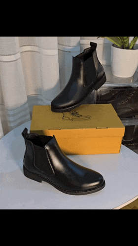 a pair of black boots sitting on a table next to a yellow box