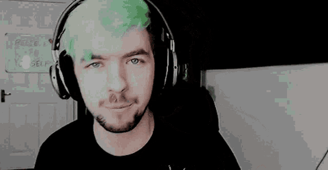 a man with green hair is wearing headphones .