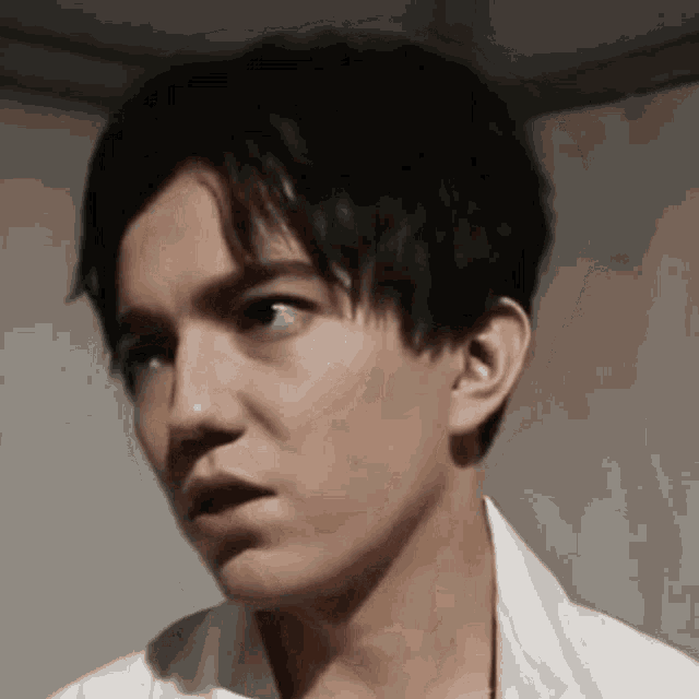 a close up of a young man 's face with a white shirt on .