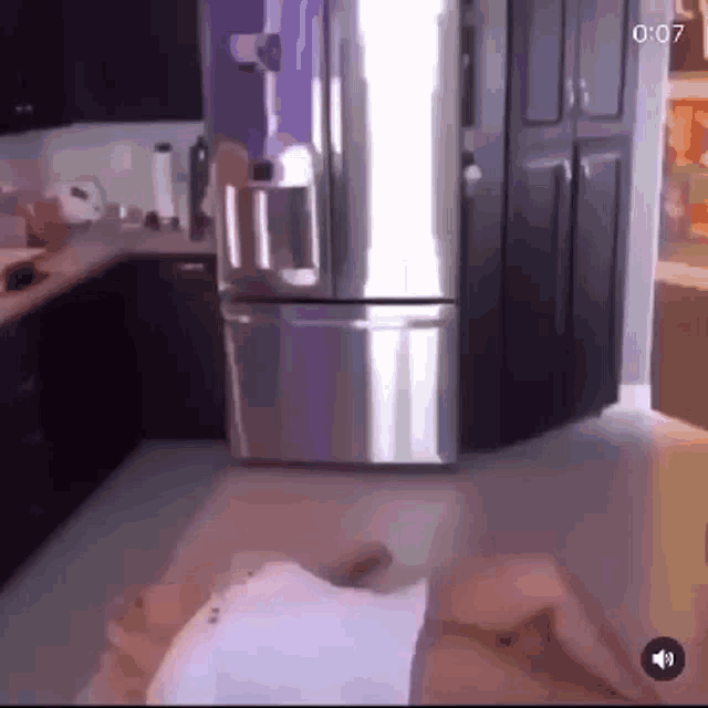 a person is laying on the floor in a kitchen in front of a refrigerator .