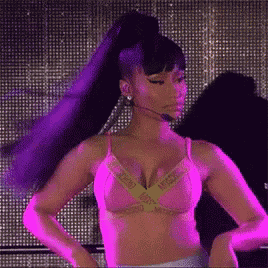 a woman in a pink bra and purple hair is standing in front of a microphone .