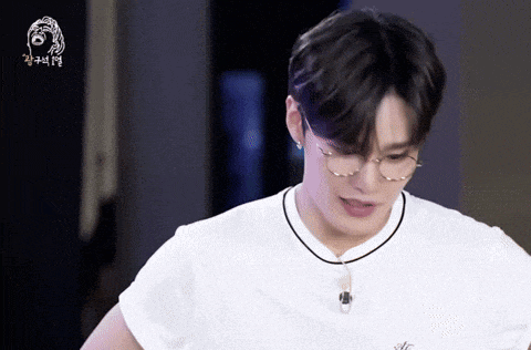 a man wearing glasses and a white t-shirt with a necklace around his neck